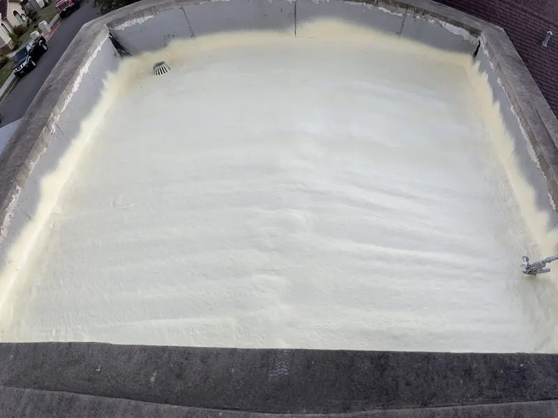 A flat commercial roof built up with sprayed polyurethane roofing foam, the white surface running to a clean parapet edge