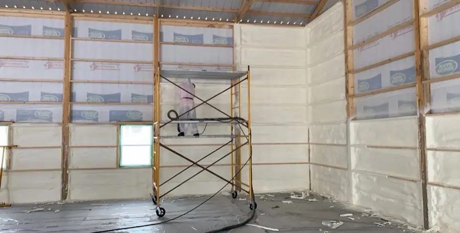 Panda Insulation crew member applying spray foam from scaffolding inside a new build