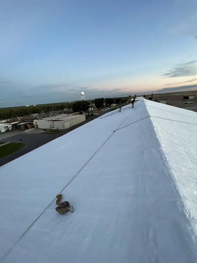 Completed white reflective roof coating on a commercial building at dusk